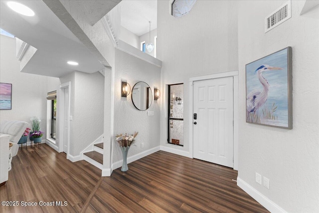 entryway with stairs, visible vents, baseboards, and wood finished floors