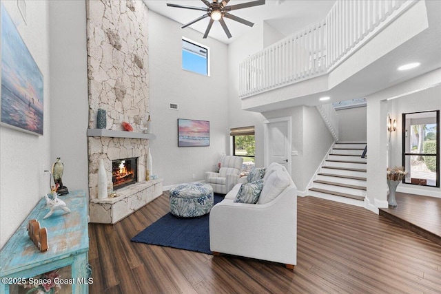 living room with plenty of natural light, a fireplace, stairway, and wood finished floors