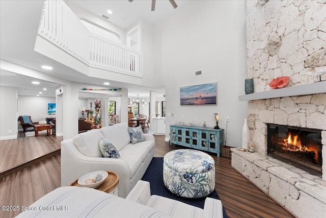 living room with a fireplace, visible vents, ceiling fan, wood finished floors, and baseboards