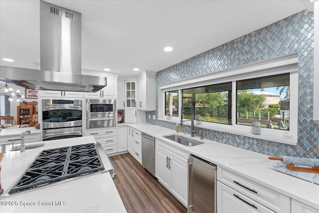 kitchen featuring island range hood, white cabinets, dark wood finished floors, stainless steel appliances, and a sink