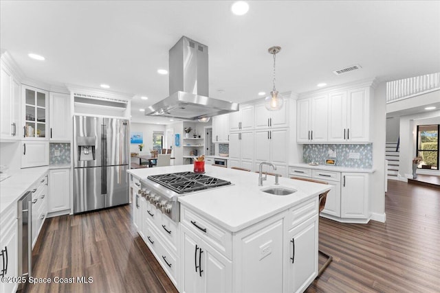 kitchen with a center island with sink, white cabinets, appliances with stainless steel finishes, island exhaust hood, and a sink