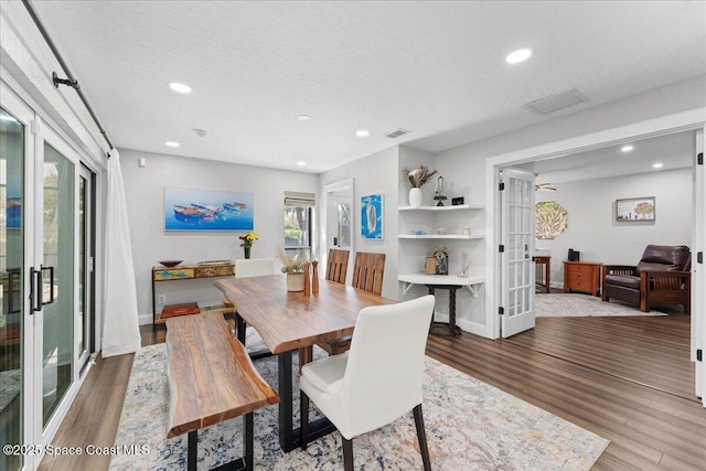 dining room featuring a textured ceiling, recessed lighting, wood finished floors, visible vents, and french doors