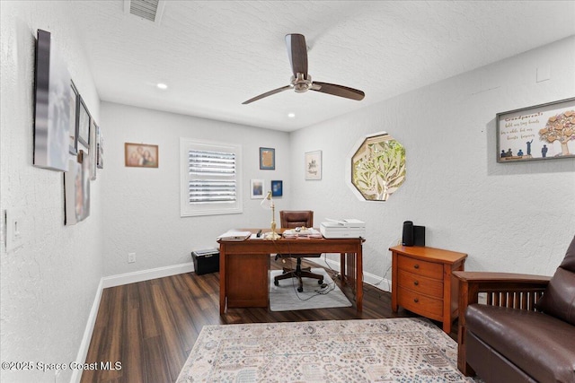 home office with a textured wall, wood finished floors, visible vents, and baseboards