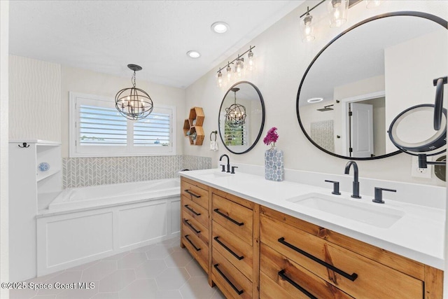 bathroom with a garden tub, a notable chandelier, a sink, and tile patterned floors