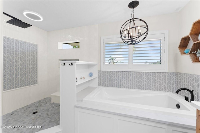 full bathroom featuring a garden tub and an inviting chandelier