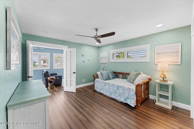 bedroom featuring multiple windows, baseboards, wood finished floors, and french doors