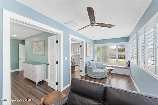 sitting room featuring a textured ceiling, dark wood-type flooring, visible vents, and baseboards