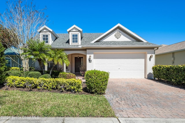 view of front of home featuring a garage, a shingled roof, decorative driveway, and stucco siding