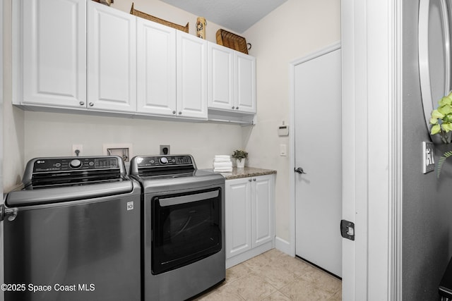 clothes washing area featuring light tile patterned floors, independent washer and dryer, and cabinet space