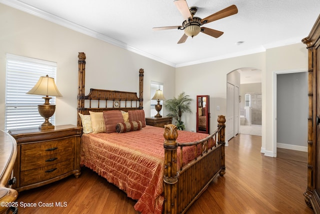 bedroom with arched walkways, baseboards, a ceiling fan, wood finished floors, and crown molding