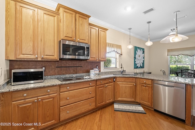 kitchen featuring crown molding, appliances with stainless steel finishes, a sink, light stone countertops, and light wood-type flooring