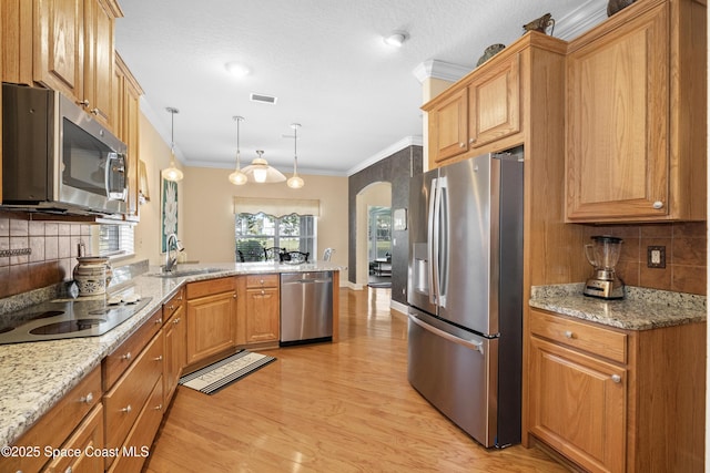 kitchen featuring arched walkways, crown molding, appliances with stainless steel finishes, a sink, and a peninsula