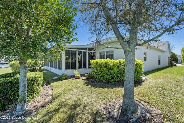 back of property with a lawn and a sunroom