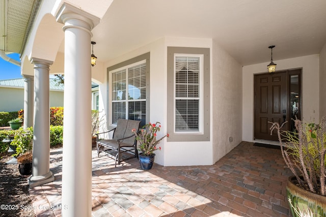 doorway to property with a porch and stucco siding