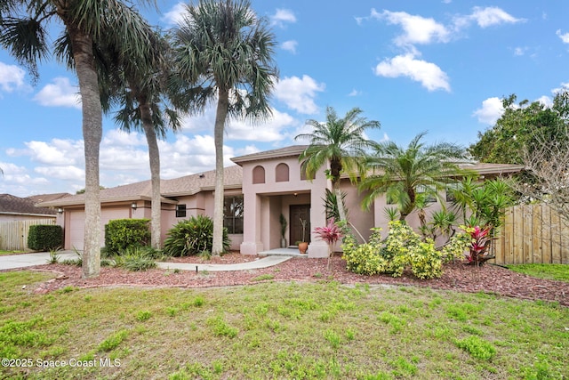 mediterranean / spanish home with an attached garage, fence, concrete driveway, stucco siding, and a front yard