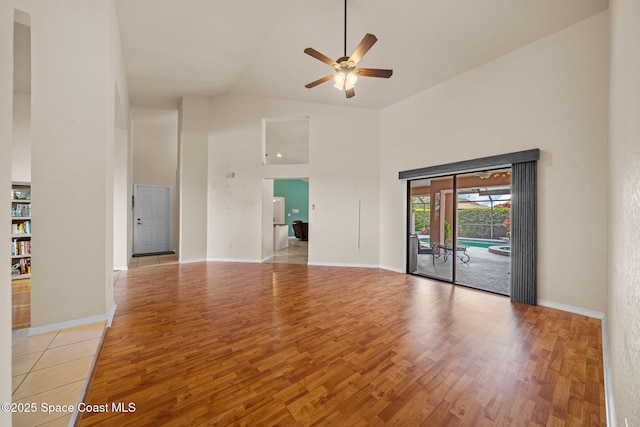 unfurnished room with baseboards, high vaulted ceiling, a ceiling fan, and light wood-style floors