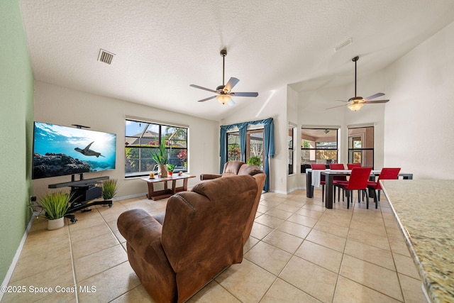 living area with a wealth of natural light, visible vents, vaulted ceiling, and light tile patterned floors