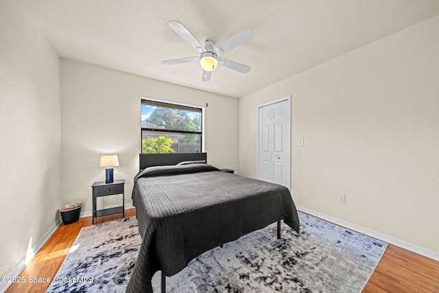 bedroom with ceiling fan, light wood finished floors, a textured ceiling, and baseboards