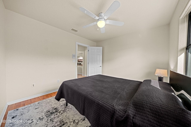 bedroom with baseboards, visible vents, a ceiling fan, and light wood-style floors