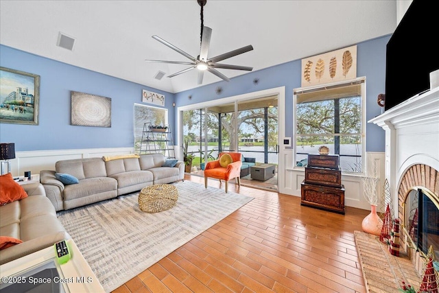 530 Carmel Dr, Melbourne, FL 32940 - living room featuring a wainscoted wall, a ceiling fan, visible vents, and a fireplace