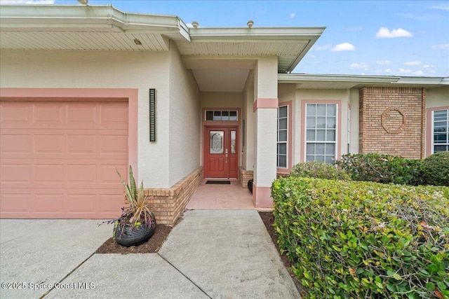 doorway to property with brick siding, stucco siding, and a garage