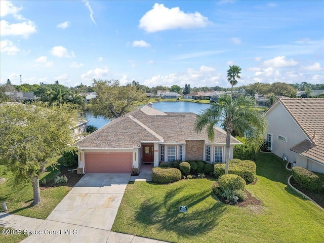 view of front of property with an attached garage, concrete driveway, a front lawn, and a water view