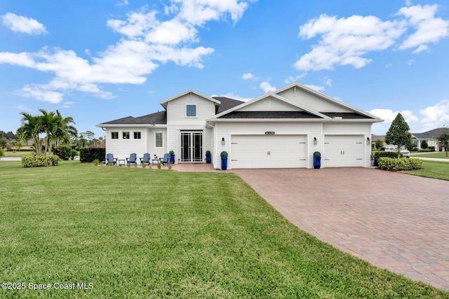 view of front of house with a front yard, decorative driveway, and an attached garage