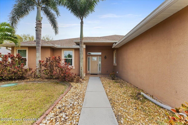 entrance to property with a yard and stucco siding