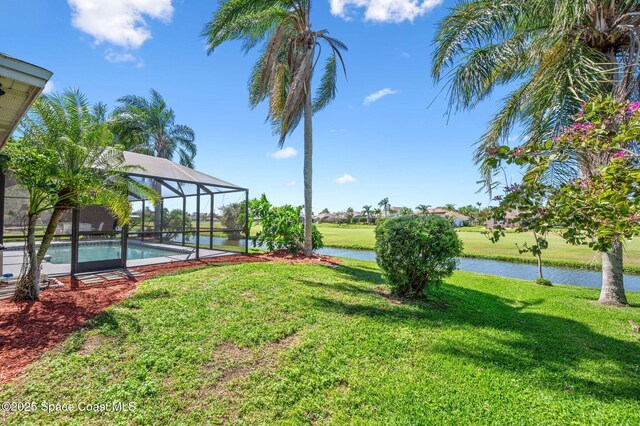 view of yard with an outdoor pool, glass enclosure, and a water view