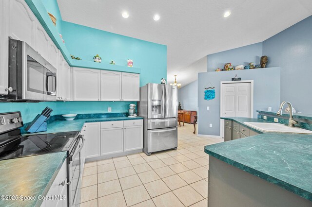 kitchen with light tile patterned floors, a sink, stainless steel appliances, white cabinetry, and dark countertops