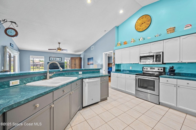 kitchen featuring a sink, dark countertops, white cabinetry, appliances with stainless steel finishes, and light tile patterned floors