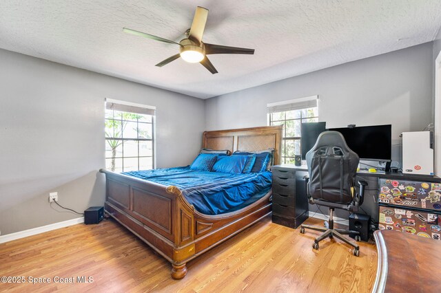 bedroom featuring light wood finished floors, ceiling fan, a textured ceiling, and baseboards