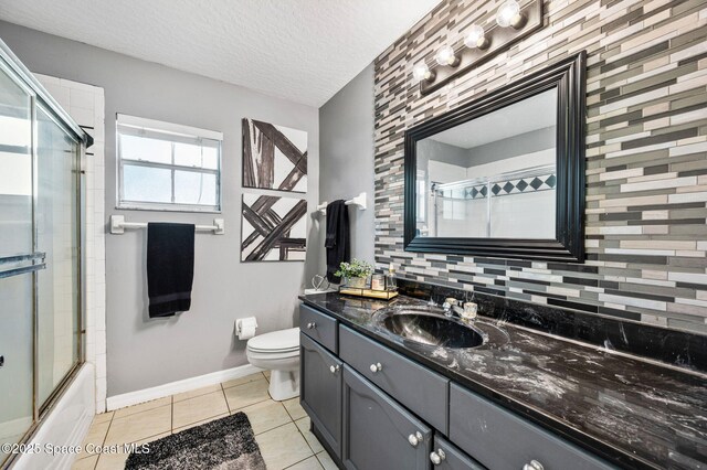 full bathroom featuring tile patterned floors, toilet, a textured ceiling, baseboards, and vanity