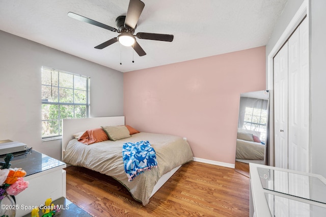 bedroom with light wood-style flooring, baseboards, a closet, and ceiling fan