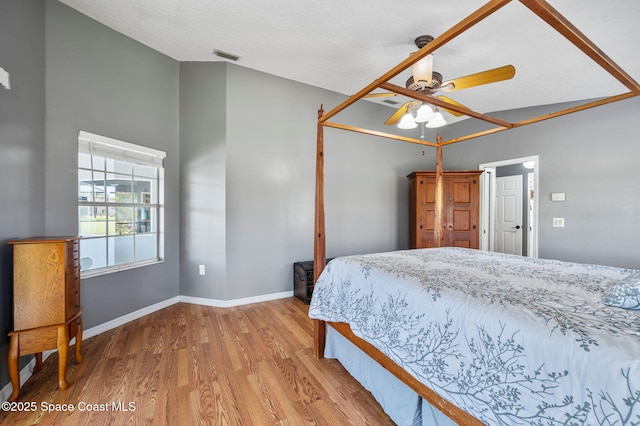 bedroom featuring visible vents, baseboards, lofted ceiling, wood finished floors, and a ceiling fan