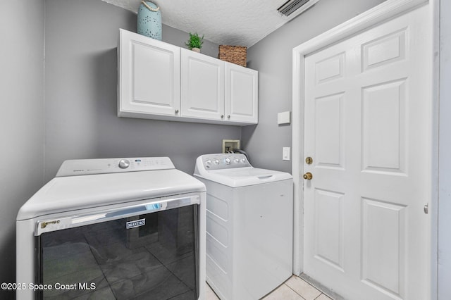 washroom with washing machine and clothes dryer, visible vents, light tile patterned floors, cabinet space, and a textured ceiling