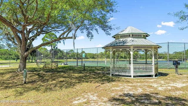 view of community with a gazebo, a tennis court, and fence