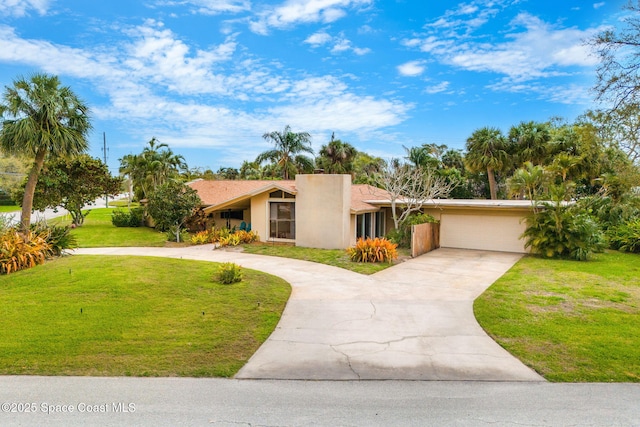 mid-century modern home with driveway, a chimney, an attached garage, a front lawn, and stucco siding