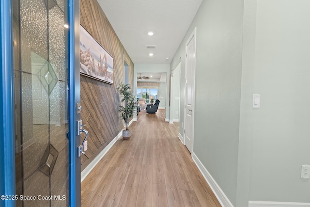 corridor featuring light wood finished floors, baseboards, and visible vents