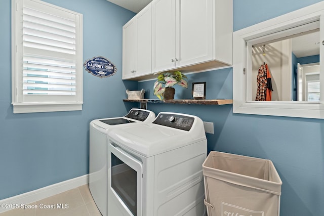 washroom featuring cabinet space, tile patterned flooring, a wealth of natural light, and washing machine and clothes dryer