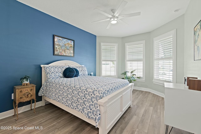 bedroom featuring ceiling fan, baseboards, and wood finished floors