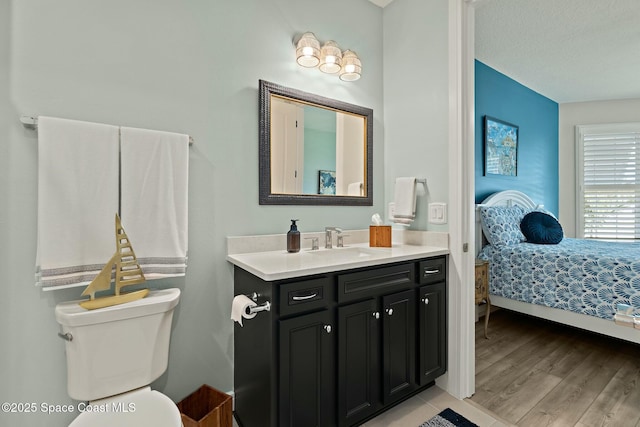 bathroom with wood finished floors, vanity, toilet, and ensuite bathroom