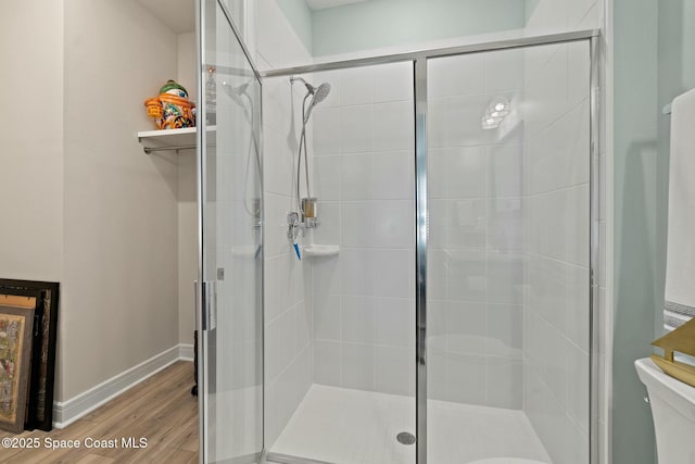 full bathroom with baseboards, a shower stall, toilet, and wood finished floors