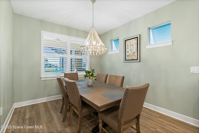 dining space with a notable chandelier, wood finished floors, and baseboards