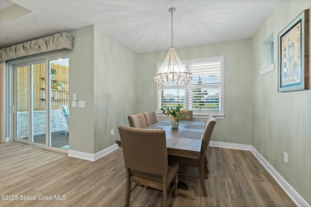 dining room featuring an inviting chandelier, baseboards, and wood finished floors