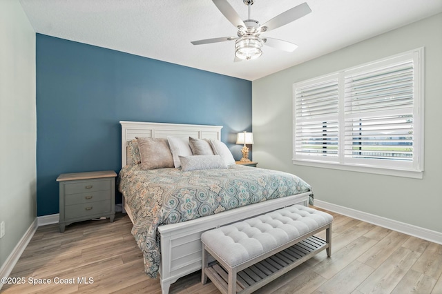 bedroom with a ceiling fan, baseboards, and wood finished floors