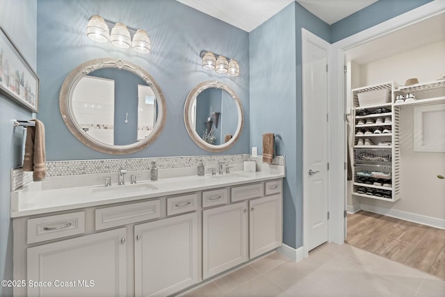 bathroom featuring double vanity, tasteful backsplash, tile patterned flooring, and a sink