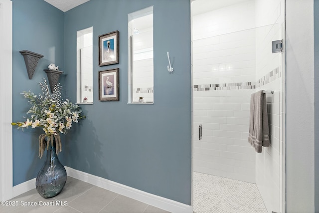 bathroom featuring a shower stall, baseboards, and tile patterned flooring