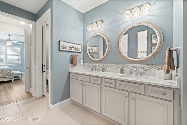 ensuite bathroom with connected bathroom, tile patterned flooring, a sink, and double vanity