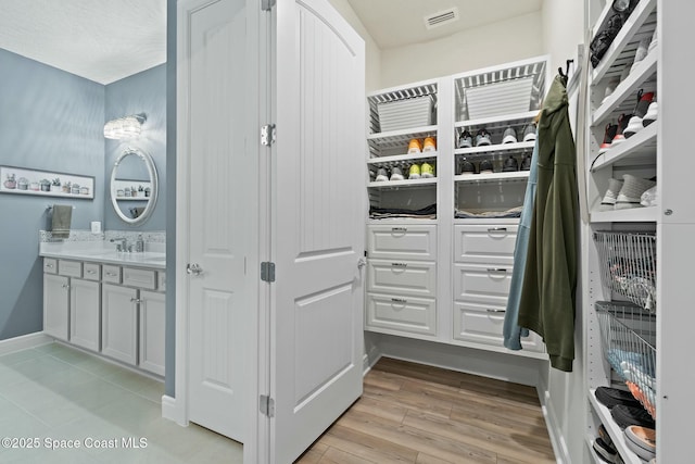 walk in closet featuring light wood-type flooring, a sink, and visible vents